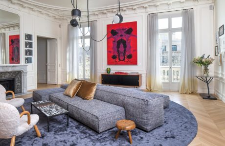 Elegant living room with ornate architectural details, modern furnishings, and vibrant artwork.