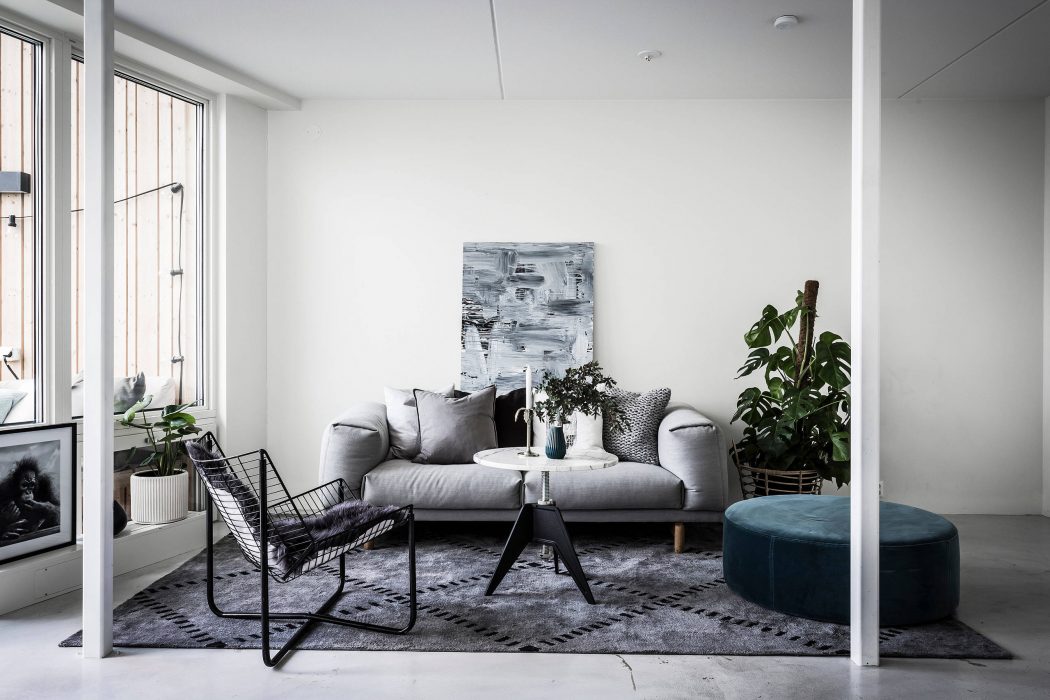 Minimalist living room with gray sofa, abstract artwork, and potted plant.