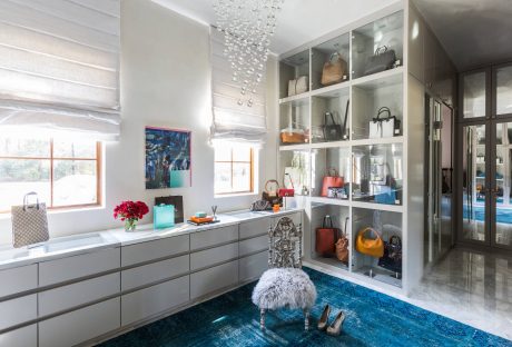 Spacious closet with glass-front cabinets, stylish rug, and crystal chandelier.