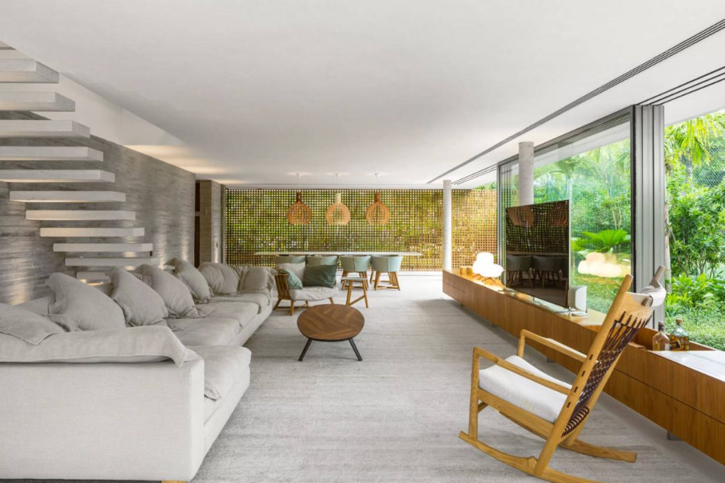 Spacious living room with cozy seating arrangement, mosaic feature wall, and greenery views.