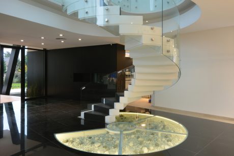 Stunning modern foyer with spiral glass and metal staircase, water feature.