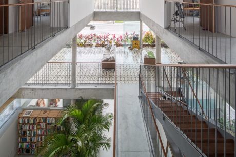 An open, airy interior with a central courtyard and lush greenery, accented by concrete and steel.