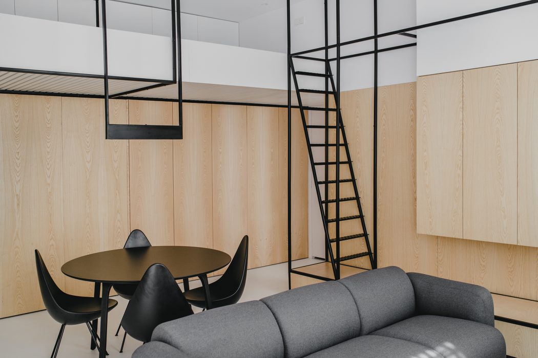 Minimalist living space with sleek metal framing, wooden paneling, and modern furniture.
