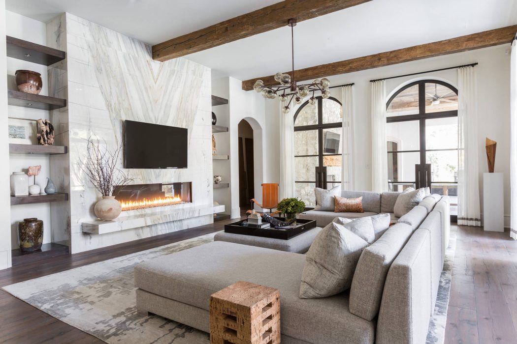 Spacious living room with stone fireplace, wood beams, and large arched windows.
