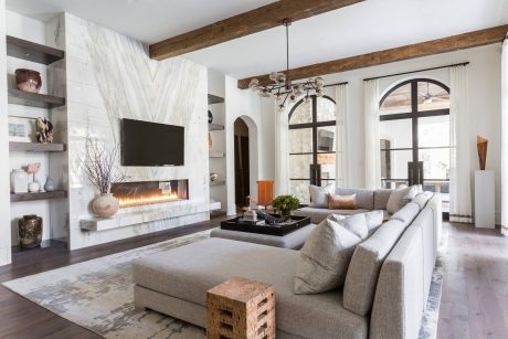 Spacious living room with stone fireplace, wood beams, and large arched windows.