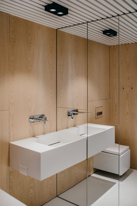Modern bathroom with minimalist design - wooden walls, dual sinks, and recessed lighting.