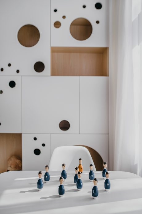 Minimalist wooden and white shelving display with stylized wooden bowling pins.