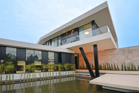 Striking modern architecture with glass walls, geometric accents, and a reflecting pool.