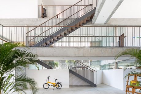 Modern architectural design featuring striking metal staircases, glass walls, and lush greenery.