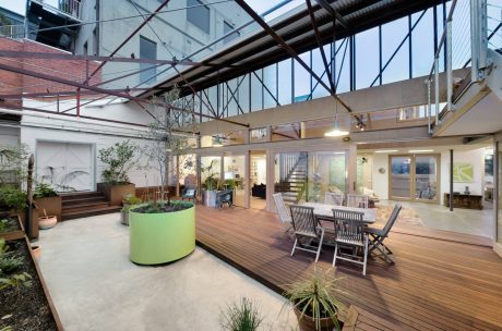 Airy open-concept interior with wooden floors, modern furniture, and greenery accents.