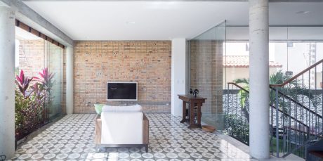 Spacious living area with exposed brick wall, patterned tile flooring, and glass walls.