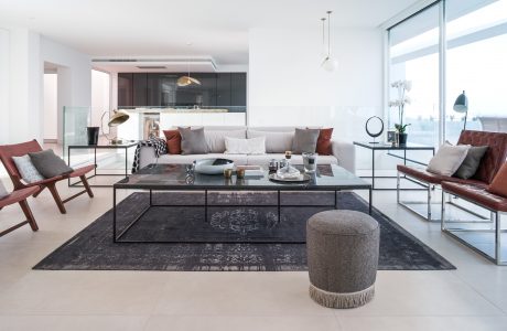 A modern living room with sleek furniture, dark accents, and large windows providing abundant natural light.