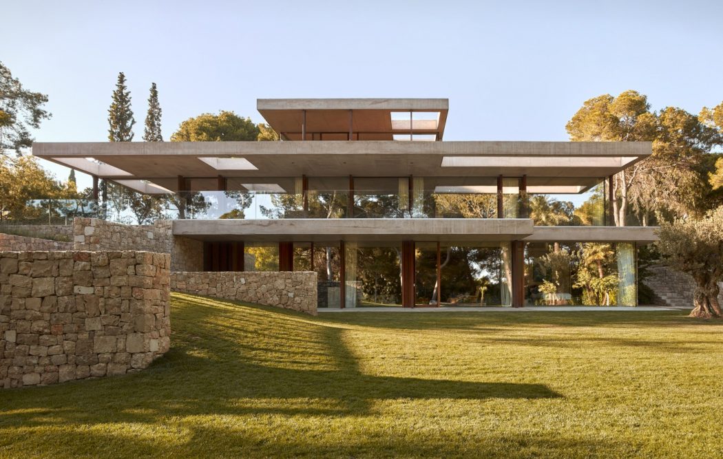 Modernist concrete and glass structure with cantilevered roofs surrounded by landscaped garden.