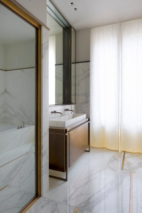 Sleek, modern bathroom with marble walls, brass fixtures, and a minimalist vanity.