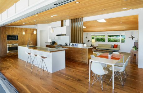 Open-concept kitchen and dining area with wooden accents, modern furnishings, and expansive windows.