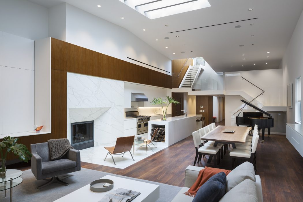 Expansive, modern living space with wood accents, white walls, and a skylight.