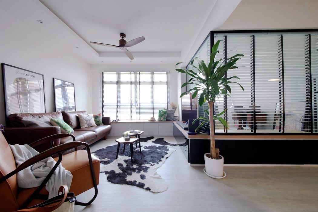 A cozy, open-concept living room with modern furnishings, large windows, and a plant accent.