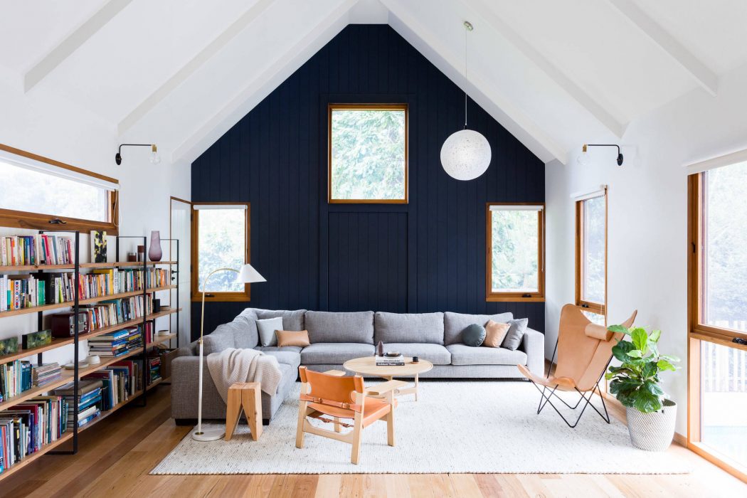 Cozy living room with vaulted ceiling, navy blue accent wall, and wooden furnishings.