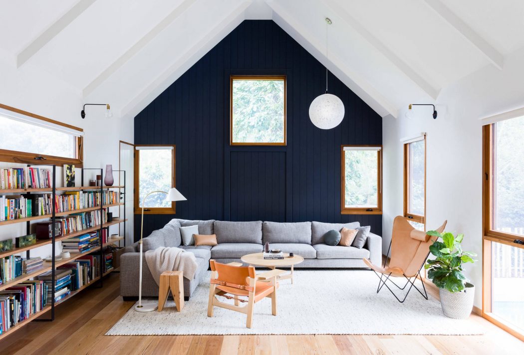 Cozy living room with vaulted ceiling, navy blue accent wall, and wooden furnishings.