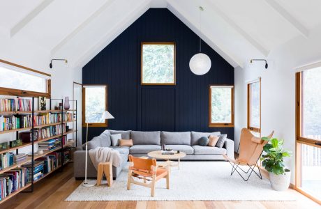 Cozy living room with vaulted ceiling, navy blue accent wall, and wooden furnishings.