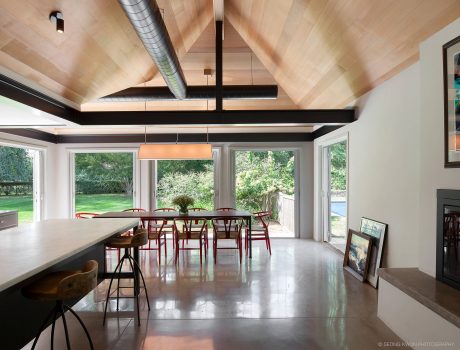 Spacious dining area with vaulted wood-paneled ceiling, large windows, and modern furnishings.