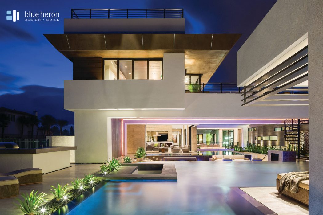 Sleek, modern architecture with open floor plan, outdoor patio, and illuminated pool.
