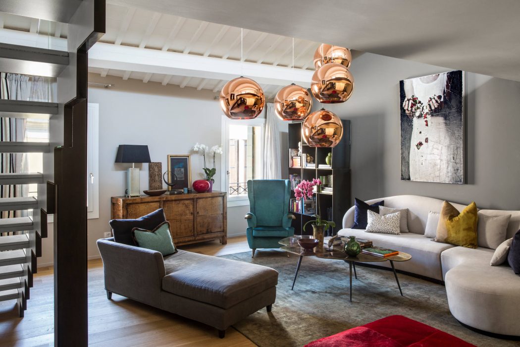Stylishly decorated living room with wooden furniture, copper pendant lights, and vibrant accents.