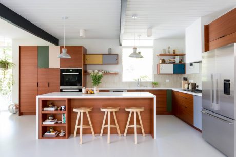 Bright, modern kitchen with wood cabinetry, white island, and colorful accents.