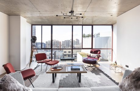 A modern living space with concrete ceiling, large windows, and minimalist furniture.