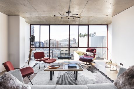 A modern living space with concrete ceiling, large windows, and minimalist furniture.