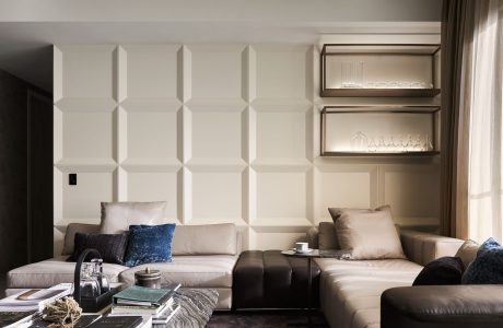 Well-designed living room featuring textured walls, shelving, and neutral-toned furniture.