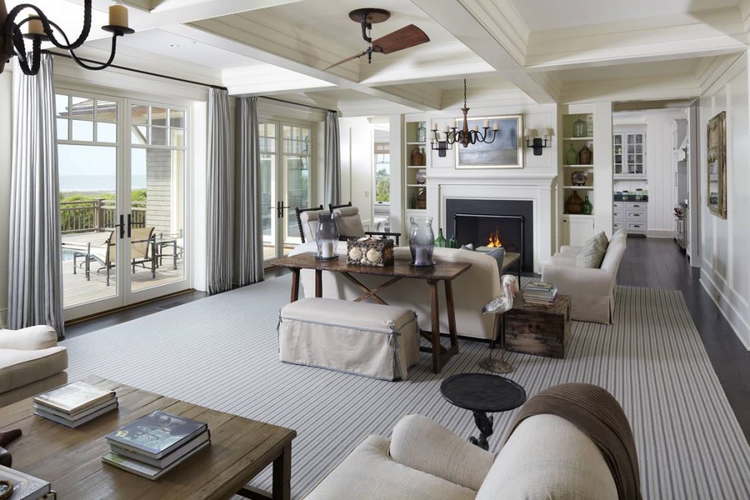 Spacious coastal living room with coffered ceiling, fireplace, and French doors leading to porch.
