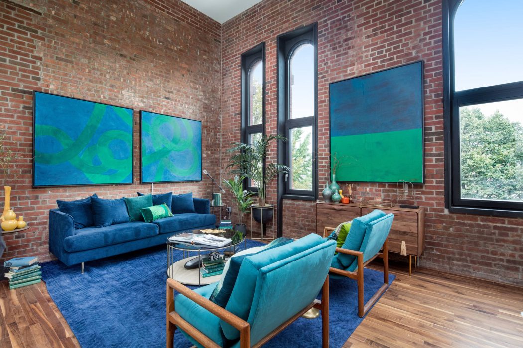 Vibrant modern living room with brick walls, large windows, and colorful abstract art.