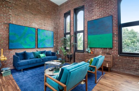 Vibrant modern living room with brick walls, large windows, and colorful abstract art.