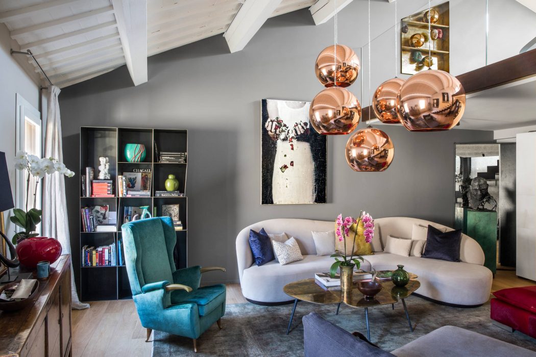Stylish open-concept living space with high ceilings, copper lighting fixtures, and eclectic decor.