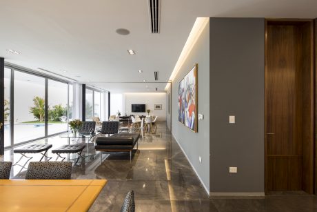 Spacious modern living room with sleek furniture, large windows, and vibrant artwork.