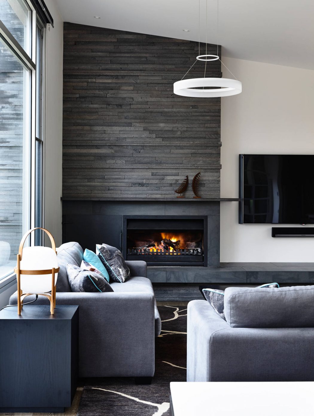 Cozy living room with sleek, modern design featuring dark wood accent wall and fireplace.