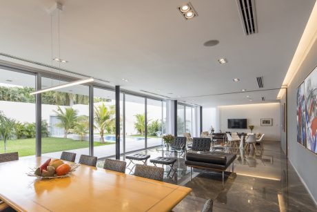 Spacious modern interior with floor-to-ceiling windows, sleek furnishings, and lush greenery views.
