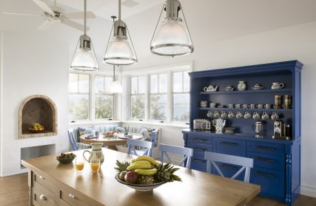 Bright, modern kitchen with blue cabinetry, pendant lights, and cozy banquette seating.