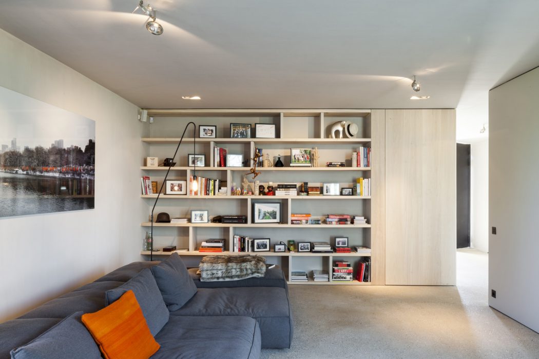 Spacious, modern living room with floor-to-ceiling shelving, cozy sofa, and artwork.