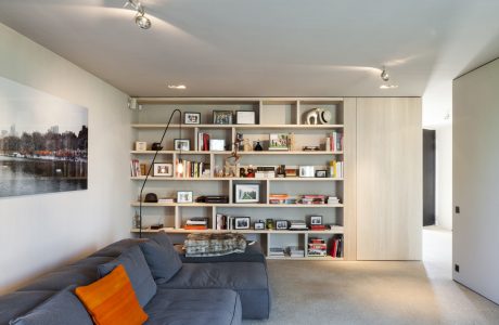 Spacious, modern living room with floor-to-ceiling shelving, cozy sofa, and artwork.