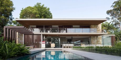 Stunning contemporary home with expansive glass walls, wooden beams, and a sleek pool.