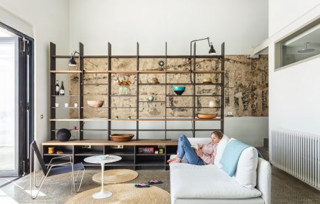 Warm, modern living space with rustic brick wall, open shelving, and plush furnishings.