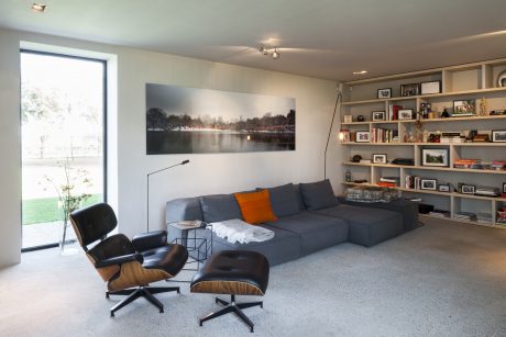 Spacious modern living room with grey sofa, wooden shelving, and large nature artwork.