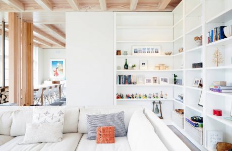 Serene living space with wooden ceiling beams, white shelving, and cozy seating.