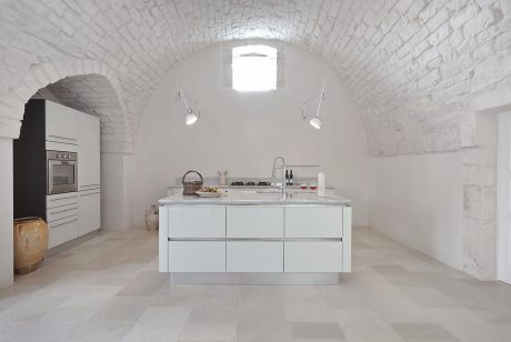 Bright, minimalist kitchen with arched white brick walls and modern cabinetry.