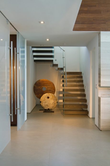 Minimalist hallway with wooden staircase and spherical sculptures, showcasing modern design.