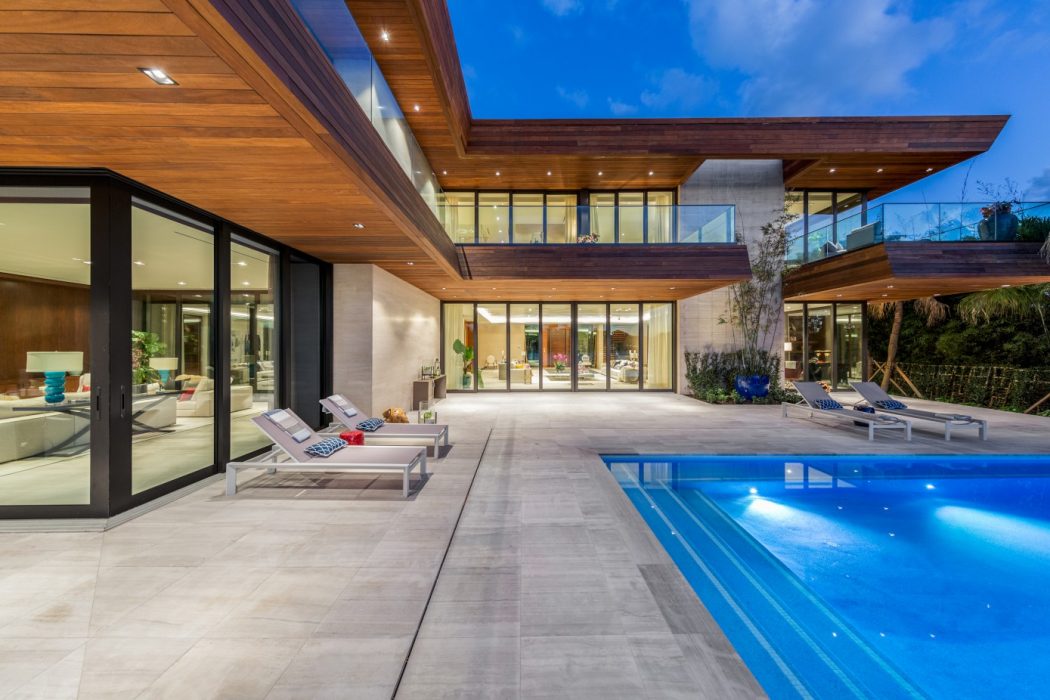 Contemporary luxury home with sleek wooden exterior, large windows, and a stunning poolside patio.