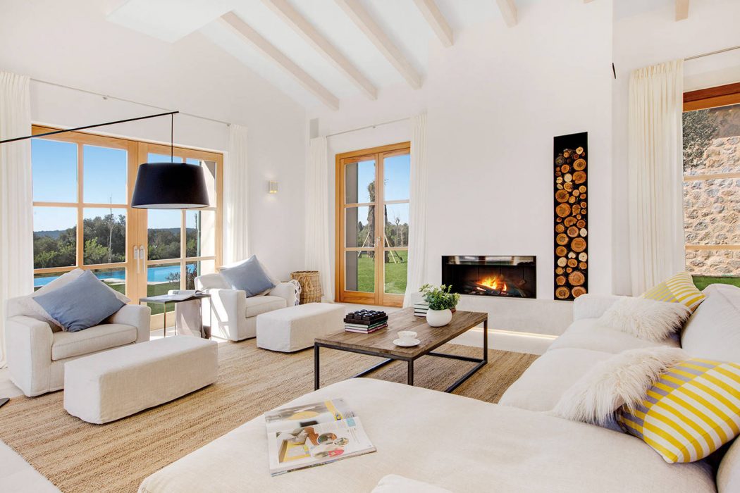 Spacious living room with vaulted ceiling, wood-framed windows, and cozy fireplace.
