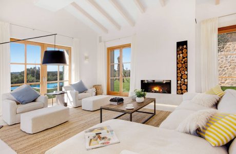 Spacious living room with vaulted ceiling, wood-framed windows, and cozy fireplace.